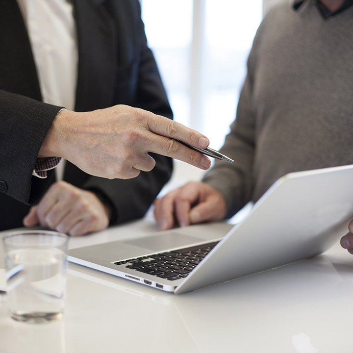 person pointing something out on a laptop to another person