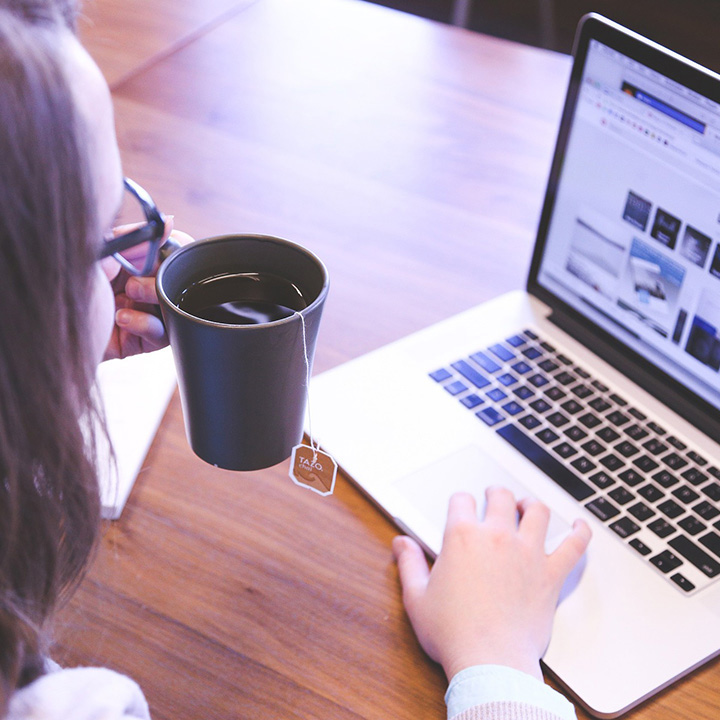 woman with a cup of tea working at her laptop