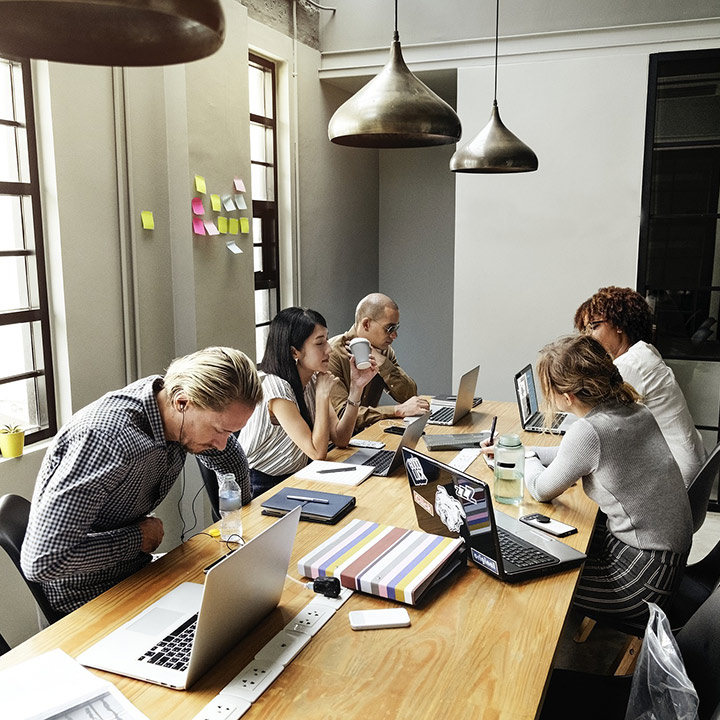 employees in a small business with their computers having a meeting